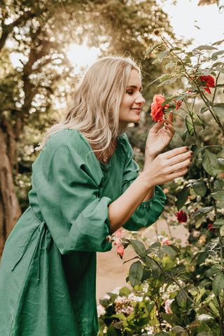 women smelling flowers in a green dress
